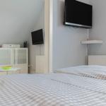 Zimmer mit Bett, Fernseher und Schrank. Decke geneigt. Wandfarbe hellblau.