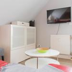 Wohnzimmer mit TV, Couch, Tisch und Fenster.