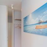 Schlafzimmer mit Kleiderschrank und Strandbild an der Wand.