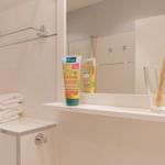 Badezimmer mit Spiegelschrank, Zahnbürsten und Handtüchern.