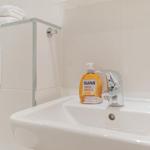 Waschbecken mit Seife, Wasserhahn und Handtuch auf Ablage.