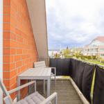 Terrasse mit Tisch und Stühlen, Sicht auf Wohngebiet und Grünflächen.