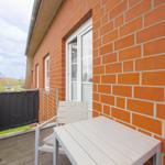 Terrasse mit Tisch und Stuhl vor roter Ziegelwand