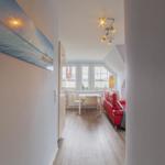 Ein Raum mit rotem Sofa, Tisch und Fenstern.