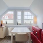 Wohn- und Essbereich mit rotem Sofa, weißem Tisch und Dachfenstern.