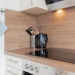 Küche mit Holzrückwand, Kochfeld und Küchengeräten.