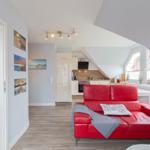 Wohnung mit rotem Sofa, Küche und Schlafzimmer im Dachgeschoss.