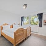 Bedroom with wooden bed, window, and wall picture.