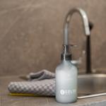 Soap dispenser with foam next to sink and towel