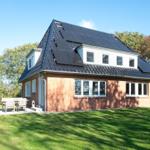 Red brick house with solar panels and terrace in the green.