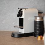 Nespresso coffee machine with milk frother and capsules on kitchen counter.