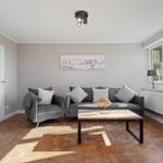 Living room with gray sofa, wooden floor, and window.