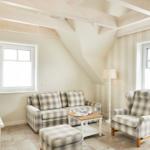 Wohnzimmer mit Sofa, Sessel und TV. Holzbalken an der Decke.