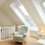 Schlafzimmer mit Dachfenstern, Sessel und Nachttisch.