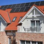 Haus mit Solaranlage, rotem Dach und Balkon mit Tisch und Stühlen.