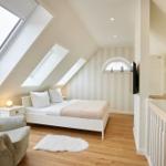 Dachgeschosszimmer mit Bett, Sessel und Dachfenstern.