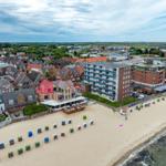 Strandpromenade mit bunten Strandkörben und Hotels direkt am Meer.