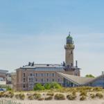 Hafenbecken mit Leuchtturm und modernem Gebäude im Hintergrund.