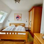 Schlafzimmer mit Dachschrägen, Doppelbett, Kleiderschrank und Fenster.