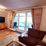 Wohnzimmer mit Sofa, Fernseher und Balkonansicht.