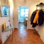 Flur mit Fliesenboden, Spiegel und Kleiderständer mit Jacken.