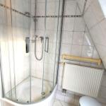 Duschkabine mit Glaswand, Heizkörper und Stuhl