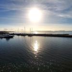 Sonnenlicht spiegelt sich auf dem Wasser. Yachten liegen im Hafen.