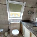 Badezimmer mit Dusche, Toilette, Waschbecken und Dachfenster.