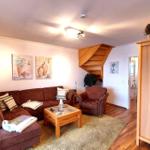 Wohnzimmer mit Sofa, Sessel, Couchtisch und Holztreppe.