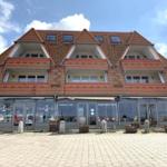 Ein Haus mit rotem Ziegeldach und Glasfassade. Geschäft im Erdgeschoss.