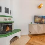 Kamin mit grünen Fliesen und TV auf Sideboard.