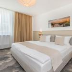 Schlafzimmer mit großem Bett, Vorhängen und Wandbild.