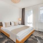 Schlafzimmer mit Bett, Nachttischen und Vorhängen.