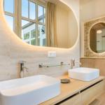 Badezimmer mit zwei Waschbecken, runden Spiegeln und Holzoberfläche.