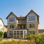 Ferienhaus mit Balkon und begrüntem Garten unter blauem Himmel