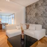 Wohn- und Essbereich mit Sofa, Tisch und Wandtapete.