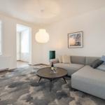 Wohnzimmer mit Sofa, Tisch und Decke. Wandbild und Hängelampe sichtbar.