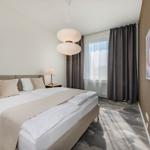 Schlafzimmer mit Doppelbett, Fenster und moderner Beleuchtung.