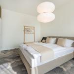 Schlafzimmer mit Bett, Nachttisch und Decke. An der Wand hängen Bilder.