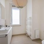 Badezimmer mit Waschbecken, Spiegel, Fenster und Heizkörper.