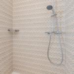 Duschkabine mit wellenförmigem Tapetenmuster und Handdusche