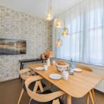 Esszimmer mit Holztisch, Stühlen und Fenster. Wand mit Tapete und Bild.