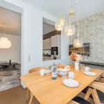 Essbereich mit Holztisch, Stühlen und dekorativer Tapete. Küche und Wohnzimmer sind sichtbar.