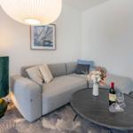 Ein Wohnzimmer mit grauem Sofa, runden Tisch und Stehlampe.