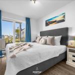 Schlafzimmer mit Bett, Nachttisch und TV. Fenster mit Blick auf Außengelände.