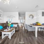 Wohn- und Essbereich mit braunem Sofa, weißen Möbeln und Holzboden.