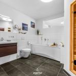 Badezimmer mit Badewanne, Toilette und integrierter Sauna.