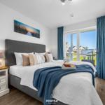 Schlafzimmer mit Bett, Nachttisch und TV. Blick auf Balkon und Garten.