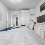 Schlafzimmer mit Bett, TV und Kleiderschrank. Wandbild zeigt Strand.