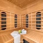 Sauna mit Holzwand und -bänken, weiße Handtücher und eine kleine Deko auf der Bank.